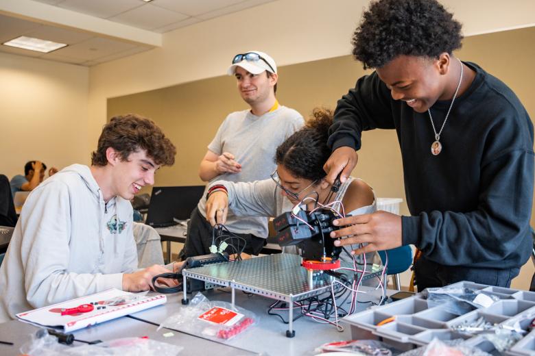 A group of students work on putting together robotics and breadboards in an ImpactLab class