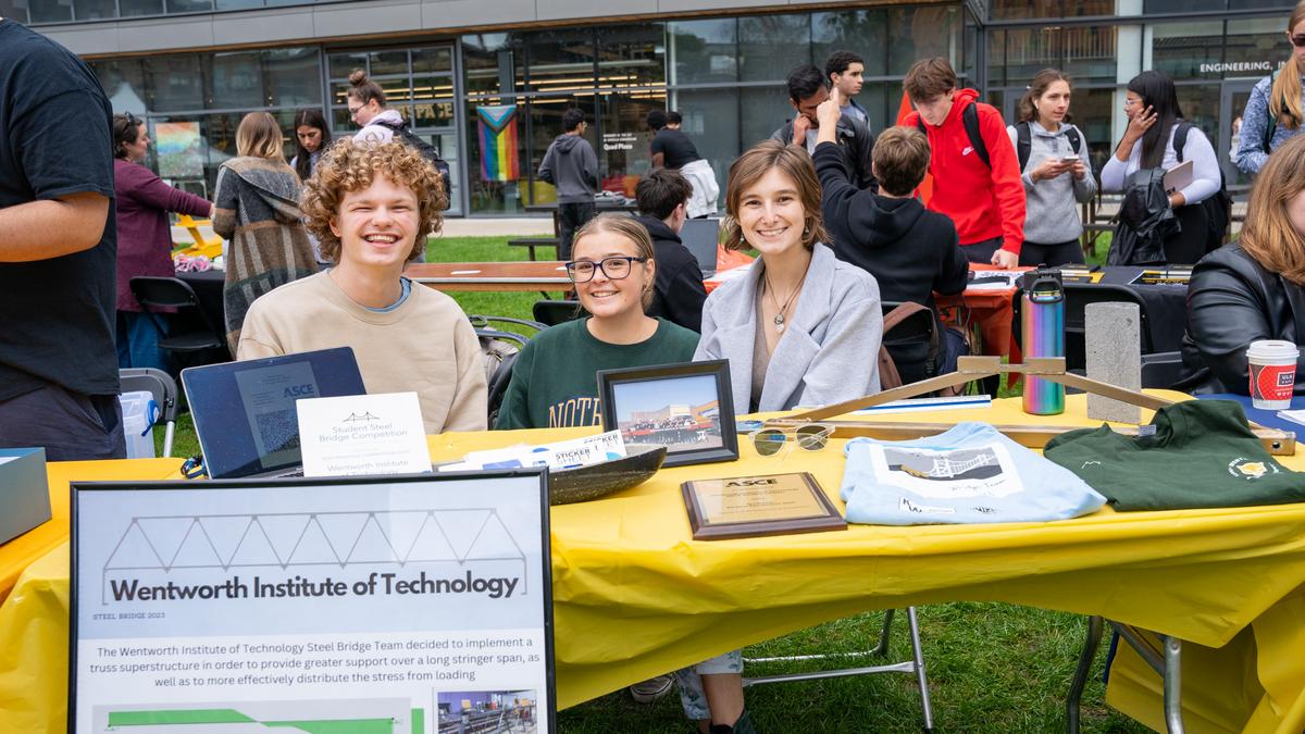 Three students sit at a table for the Student Bridge Club during the student involment fair on the quad.