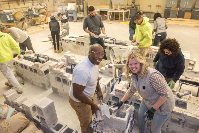 man and woman building cinder block wall