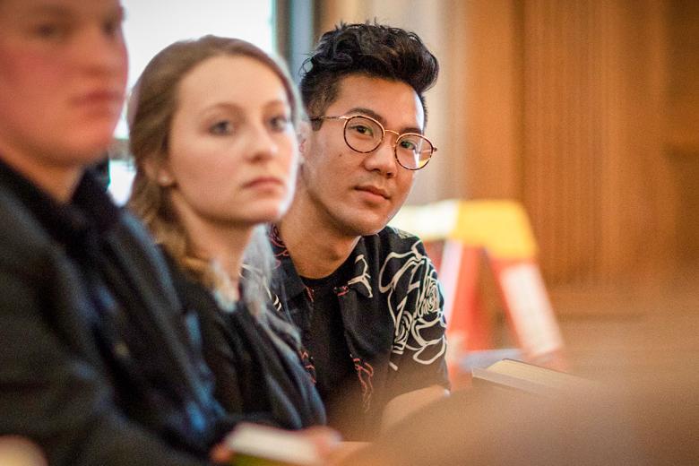 A male Architecture is in focus while a female and male student sit beside him are out of focus. 