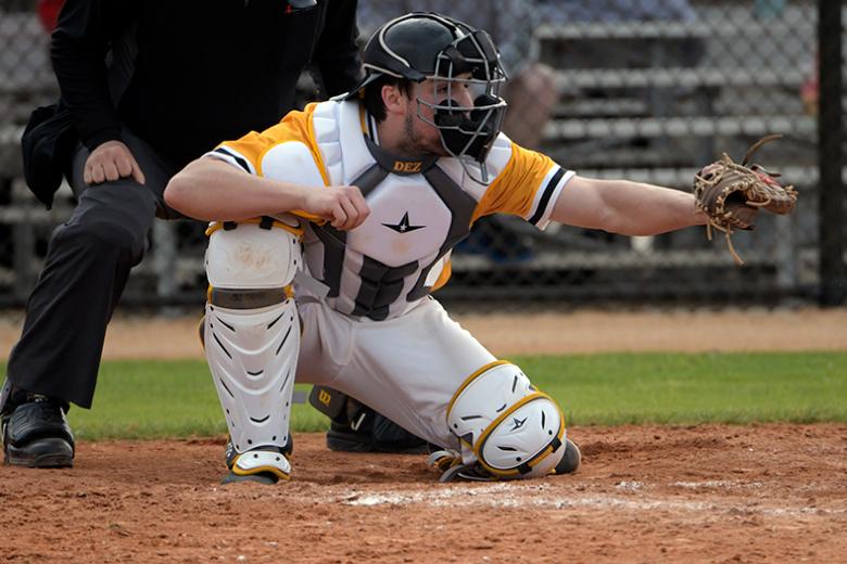 man playing baseball in catcher's uniform