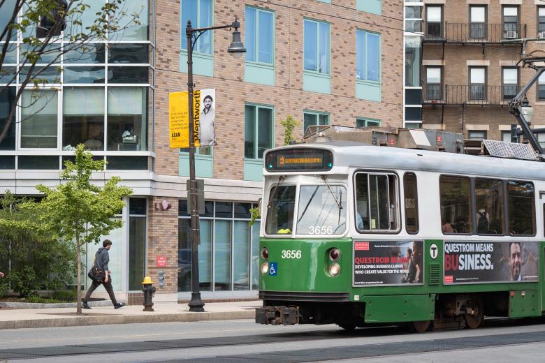 a green train moves past a building