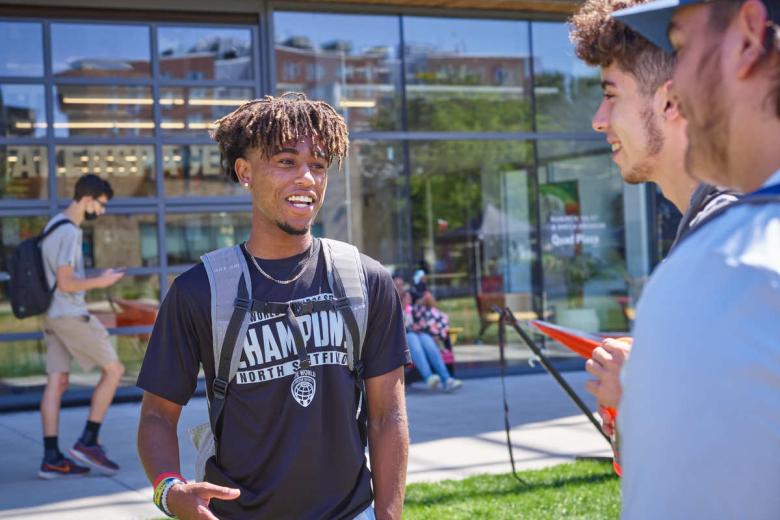 Three male students talk on the quad in front of the CEIS building