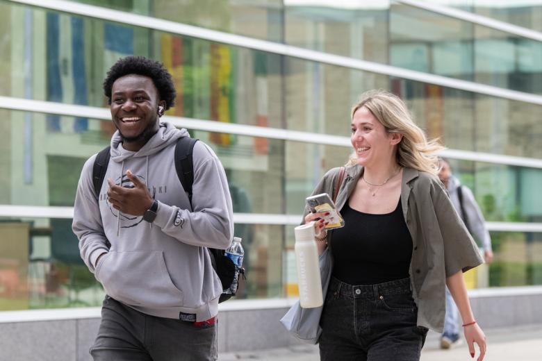 A man and woman walk next to Beatty hall on a spring afternoon.