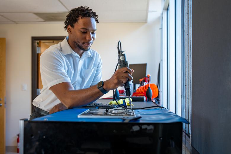 A student worker repairs a laptop at Tech Spot