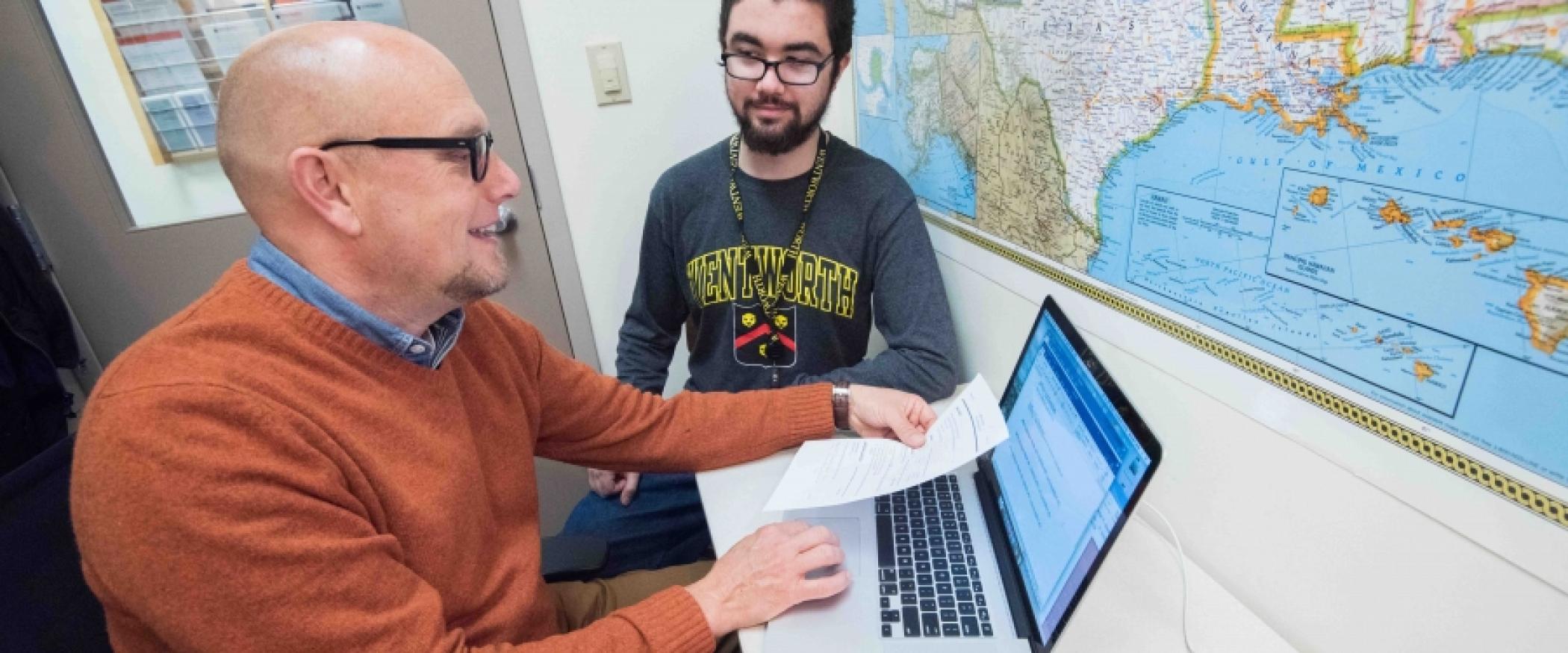 two men sitting at a computer