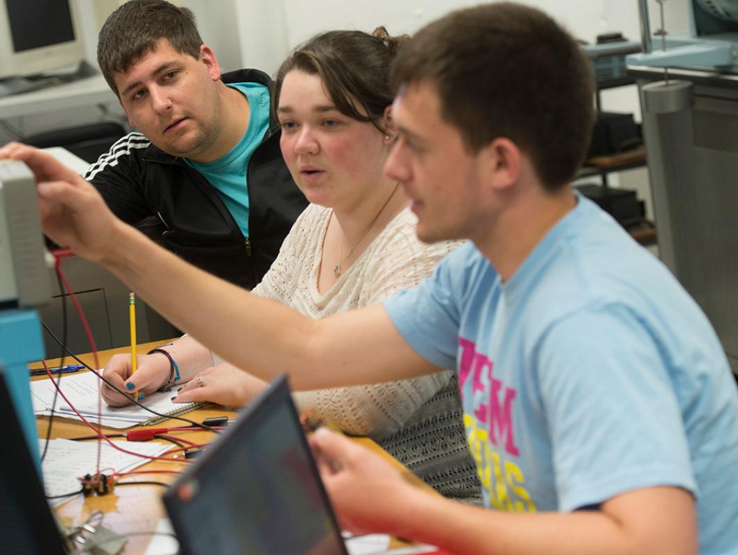 Students and instructor work on electrical engineering testing equipment.