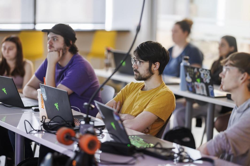 Students attend a lecture with their laptops opened in front of them.
