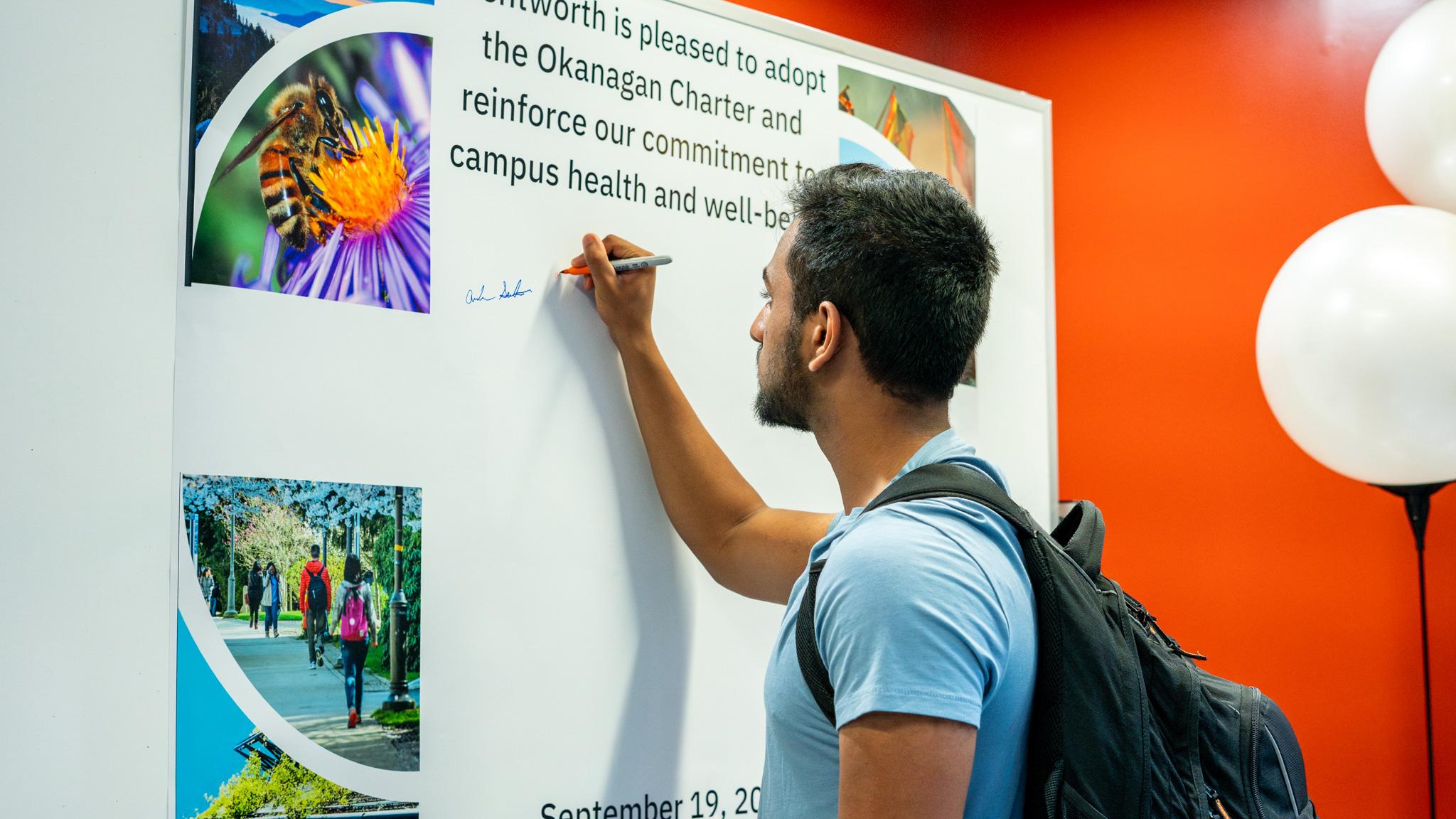 Student Signing Okanagan Charter Poster for Event 